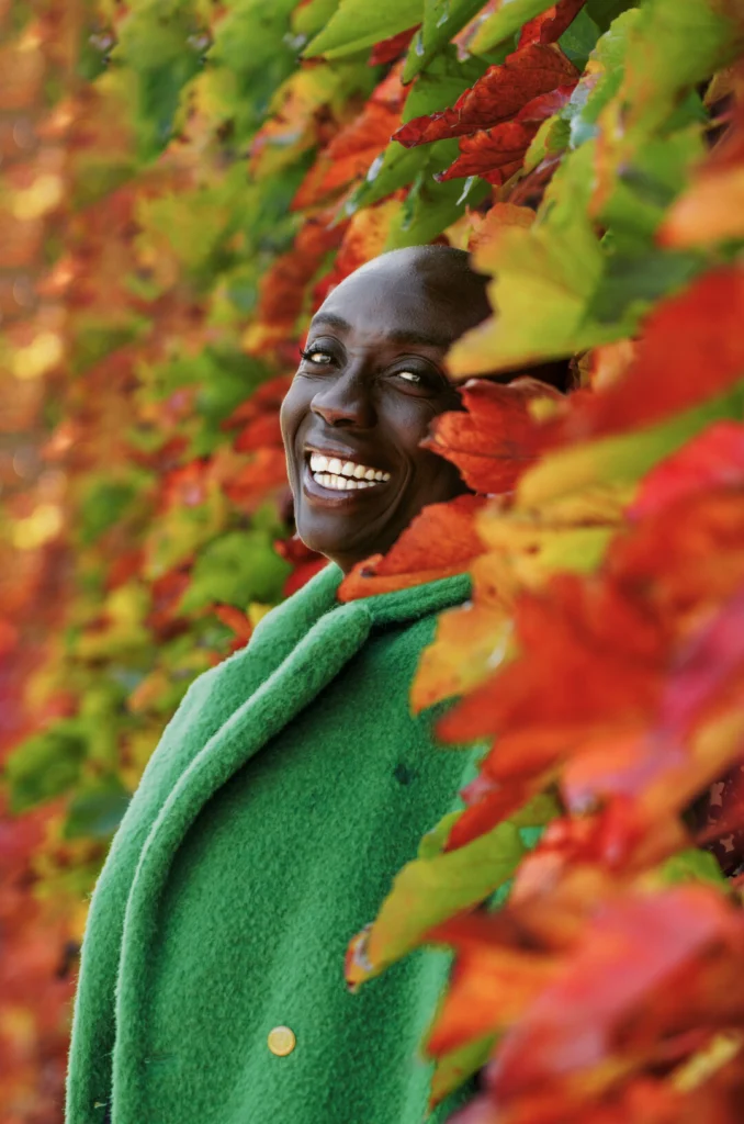 Portrait lumineux d’une femme souriante entourée de feuillages d’automne, capturé dans une ambiance naturelle et chaleureuse à Marseille.