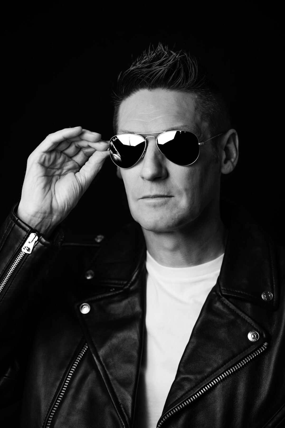 Portrait noir et blanc d’un homme en blouson en cuir et lunettes de soleil, capturant un style rock et mystérieux à Marseille.