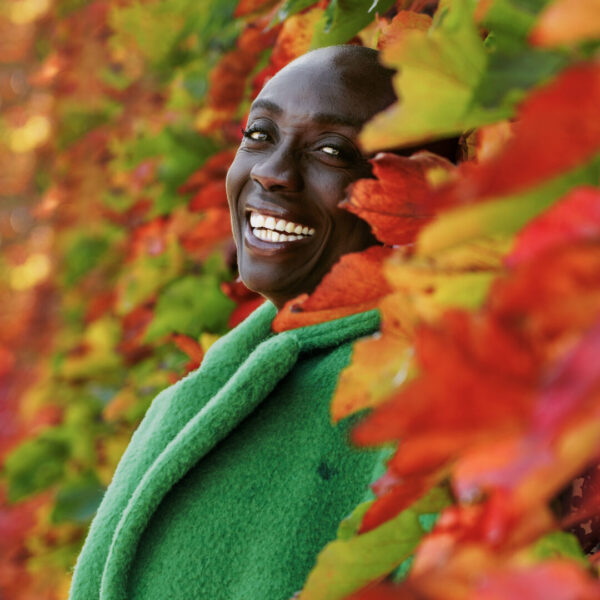 Ma vision de la photographie : comment je capture vos plus beaux moments 2 Portrait lumineux d’une femme souriante entourée de feuillages d’automne, capturé dans une ambiance naturelle et chaleureuse à Marseille.