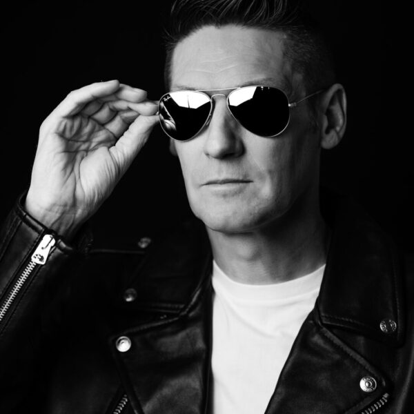 Photographe Portrait Marseille 6 Portrait noir et blanc d’un homme en blouson en cuir et lunettes de soleil, capturant un style rock et mystérieux à Marseille.